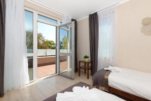 ブダペストにあるホリデー ビーチ ブダペスト ウェルネス ホテル ウィズ サウナ パークのベッド2台とバルコニーが備わるホテルルームです。