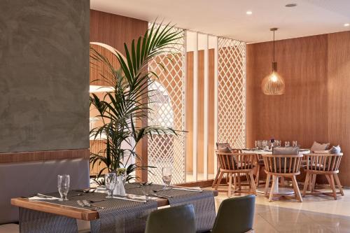 a dining room with tables and chairs and a plant at Atlantica Marmari Palace in Mastichari