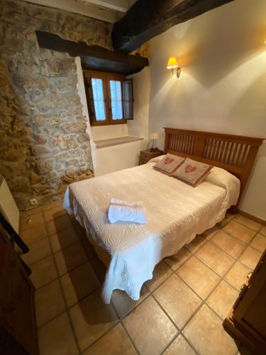 een slaapkamer met een bed in een kamer met een stenen muur bij Apartamentos Rurales La Antigua Fonda in Candelario