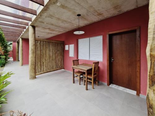 a patio with a wooden table and chairs next to a red wall at Pousada Tubes Maresias in Maresias