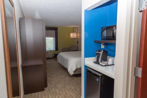 a hotel room with a bed and a room with a microwave at Holiday Inn Express Clayton Southeast Raleigh by IHG in Garner