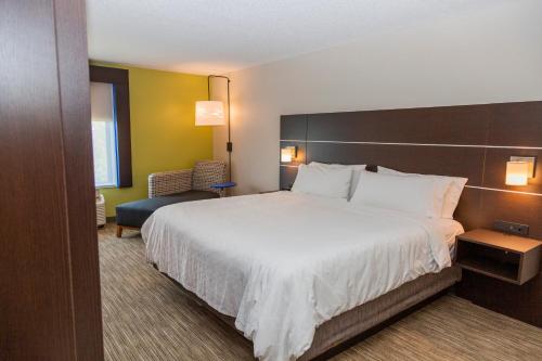 a hotel room with a large bed and a chair at Holiday Inn Express Clayton Southeast Raleigh by IHG in Garner
