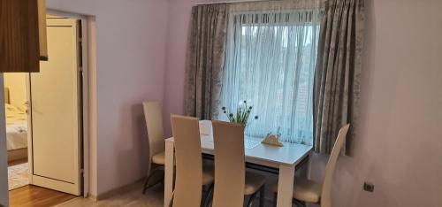 a dining room with a table and chairs and a window at Апартамент Заря in Haskovo