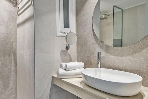 uma casa de banho com um lavatório branco e um espelho. em Atlantica Marmari Palace em Mastichari