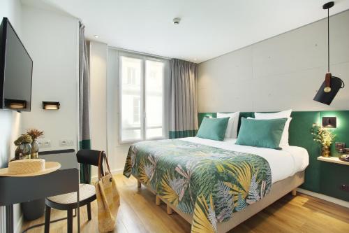 Habitación de hotel con cama, escritorio y mesa. en Le Basile Hôtel, en París