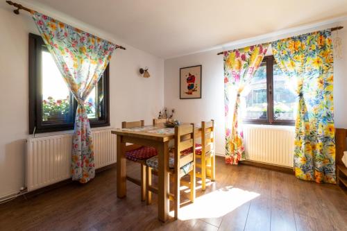 une salle à manger avec une table et deux fenêtres dans l'établissement Sunset Cottage, à Braşov