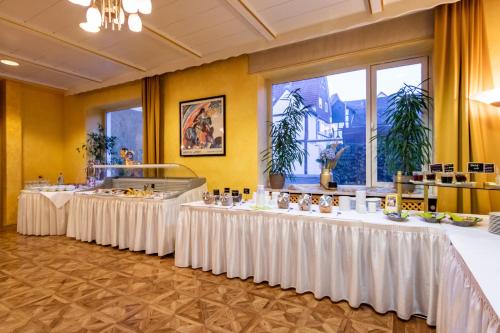 a row of tables with white table cloths in a room at Hotel Goldflair am Rathaus in Korbach