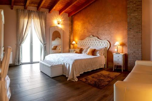 a bedroom with a white bed and a large window at Agriturismo le Fontanelle da Valente in Montichiari
