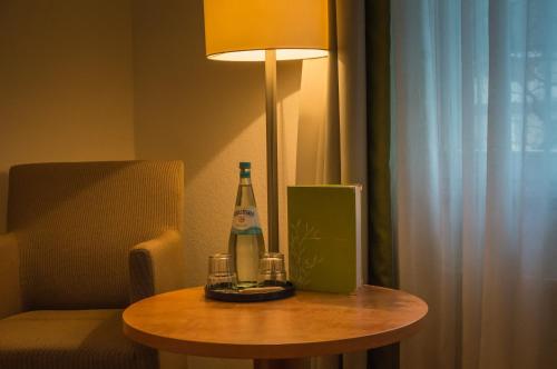 a bottle of wine on a table next to a lamp at Hotel Mingarden in Düsseldorf