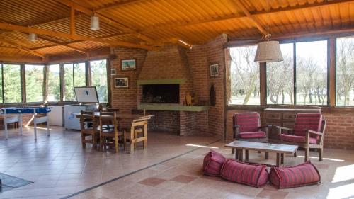 sala de estar con mesas, sillas y chimenea en Yerba Buena casas de campo - Nono en Nono