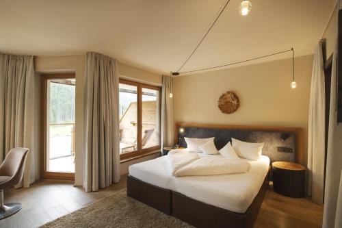 a bedroom with a bed and a large window at Almhof Family und Wellness Resort in Gerlos