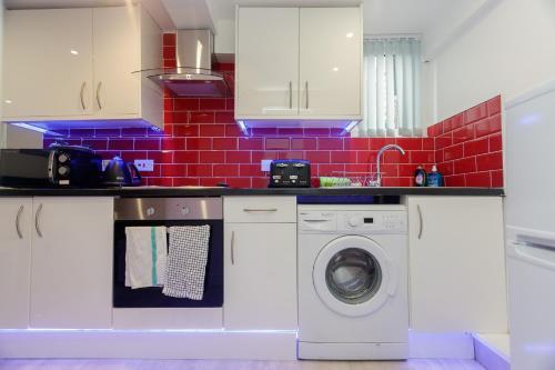 uma cozinha com uma máquina de lavar roupa e uma parede de tijolos vermelhos em AMIRI HOUSE APARTMENTs em Leeds