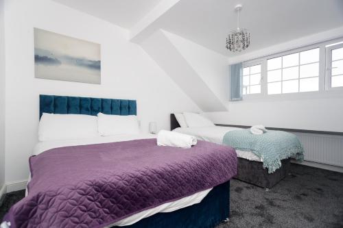 Duas camas num quarto com paredes brancas e janelas em AMIRI HOUSE APARTMENTs em Leeds