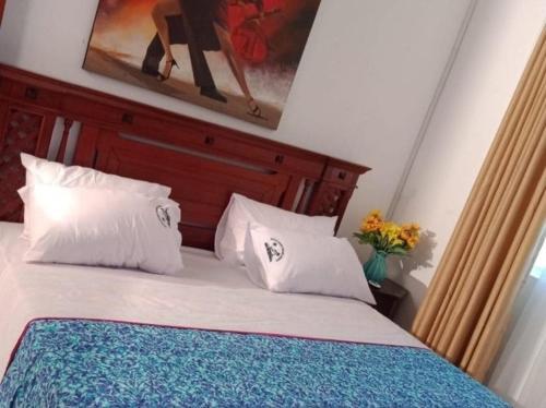 ein Schlafzimmer mit einem Bett mit weißen Kissen und einem Gemälde in der Unterkunft B2 Royal Palm apartments - Mtwapa in Mtwapa