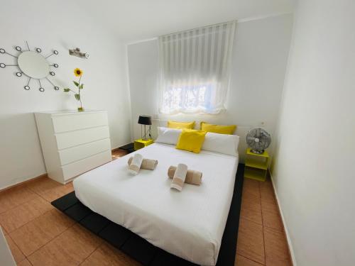 een slaapkamer met een groot wit bed met gele kussens bij Bungalow Los Porches by SunHousesCanarias in Maspalomas