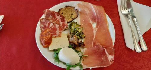 a plate of food with meat and cheese on a red table at Hotel Grandinetti in Parenti