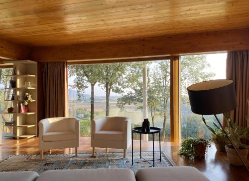 sala de estar con 2 sillas y ventana grande en Dal Gheppio - Nido con vista, en Albettone