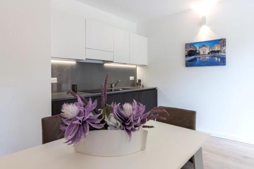 a kitchen with a white table with purple flowers at Residence La Torre con private park in Trieste