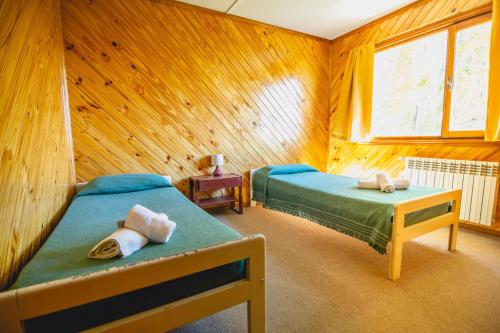 エル・カラファテにあるBla Guest Houseの木製の部屋にベッド2台が備わるベッドルーム1室