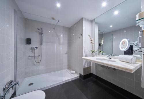 a bathroom with a shower and a sink and a tub at Golden Residence Hotel in Funchal