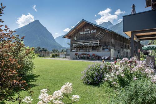 a building with mountains in the background with a yard at Gästehaus Dreier in Neukirchen am Großvenediger