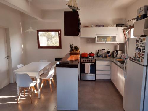 a kitchen with a table and a white refrigerator at Duplex Rio Lujan CUBE in Belén de Escobar
