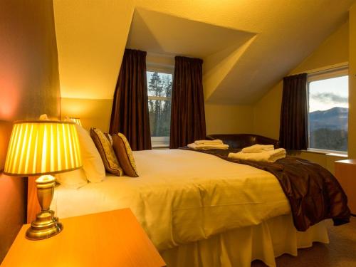 a bedroom with a bed with a lamp and a window at Craglands Guest House in Keswick