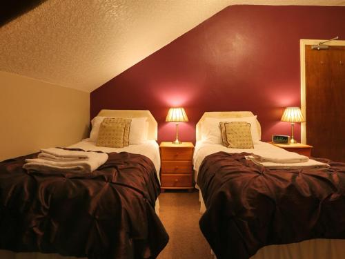 a bedroom with two beds and a red wall at Craglands Guest House in Keswick