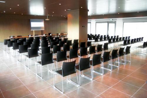 a conference room with black chairs and a podium at UNA HOTELS Le Terrazze Treviso Hotel & Residence in Villorba