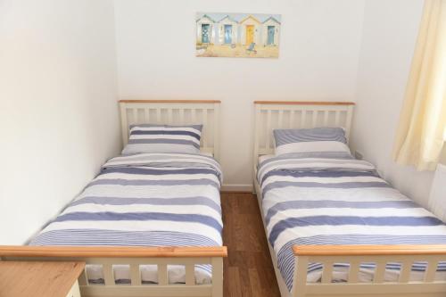 dwa łóżka w małym pokoju z obrazem na ścianie w obiekcie Ogof Aberporth w mieście Aberporth