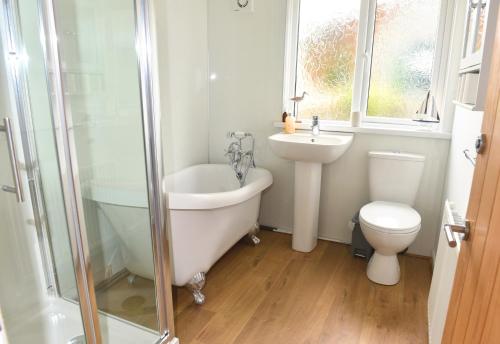 a bathroom with a tub and a sink and a toilet at Ogof Aberporth in Aberporth