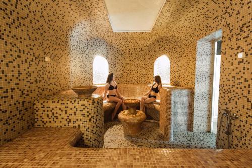 two women in bathing suits sitting in a bathroom at Hunter's Lodge in Padure