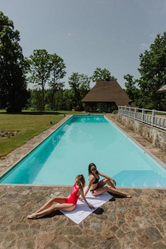 two girls laying on a towel in a swimming pool at Hunter's Lodge in Padure