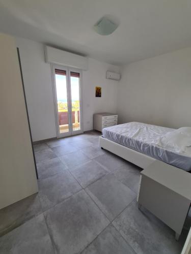 a white bedroom with a bed and a window at La villetta vista mare in Bisceglie