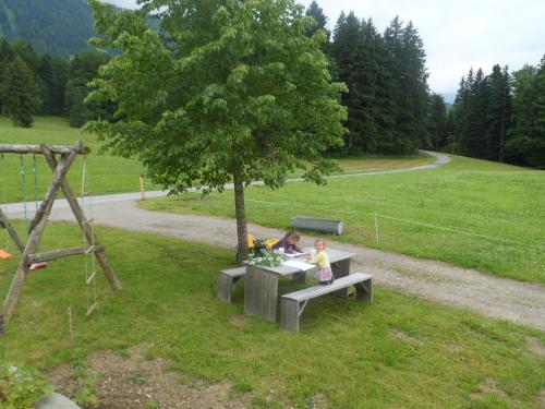 two children sitting at a picnic table under a tree at Berghof Vöglerbrand in Andelsbuch