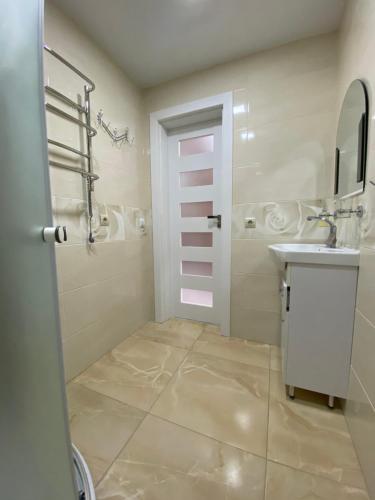 ein Bad mit einem Waschbecken und einer Dusche mit einem Spiegel in der Unterkunft Апартаменти Золота Баня 5 in Schidnyzja