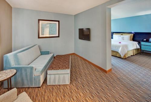 a hotel room with a bed and a couch and a chair at Crowne Plaza Hotel Glen Ellyn/Lombard by IHG in Glen Ellyn