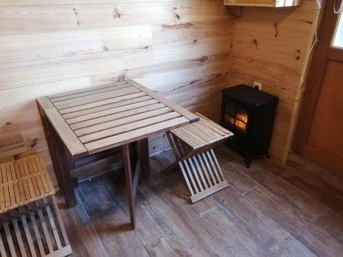 uma mesa de madeira e um banco ao lado de um fogão em patrice et chrstel Cabane en bois em Chatuzange-le-Goubet