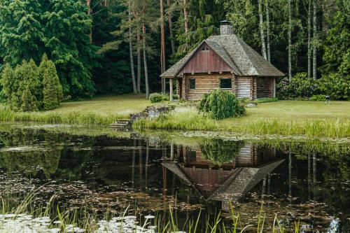 una cabaña de madera junto a un estanque con lirios en Log Cabin en Kuldīga