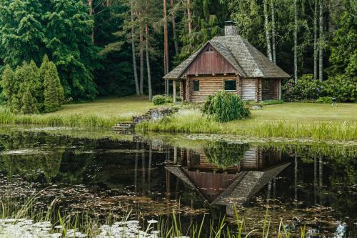 uma cabana de madeira ao lado de um lago com lírios em Log Cabin em Kuldīga