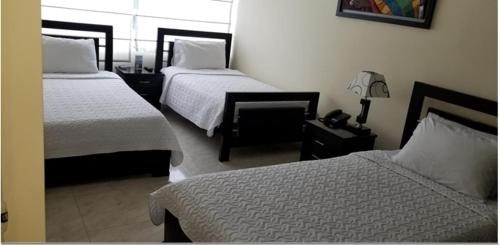 a hotel room with two beds and a lamp at Hotel Sweet Home in Bogotá