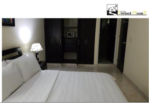 a bedroom with a large white bed and a lamp at Hotel Sweet Home in Bogotá
