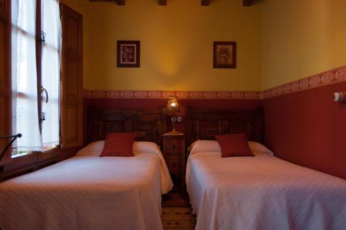 two beds in a room with yellow walls and windows at Casa Lolo de Villaviciosa in Camoca