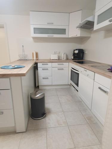 a kitchen with white cabinets and a trash can at Gemütlich ruhig und zentral durch Bahnhof in Bordesholm