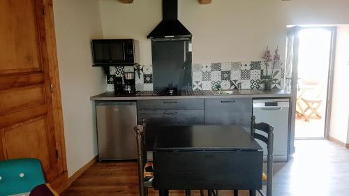 a kitchen with a table and a stove top oven at Chez Francine La Chenevière in Saint-Rémy-de-Chargnat