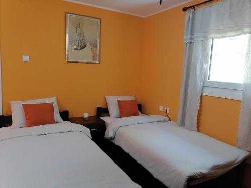 Ce lit se trouve dans un dortoir doté de murs orange et d'une fenêtre. dans l'établissement Apartman IVANA, à Vrdnik