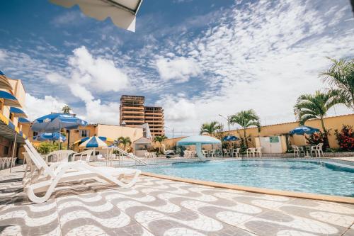 a swimming pool with lounge chairs and umbrellas at Hotel Triângulo in Caldas Novas