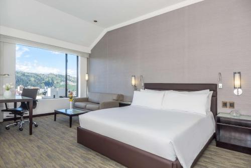 a hotel room with a large bed and a large window at NH Collection Quito Royal in Quito