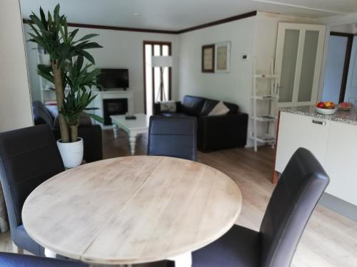 comedor y sala de estar con mesa de madera y sillas en Roodborstje 4 persoonschalet Putten en Putten