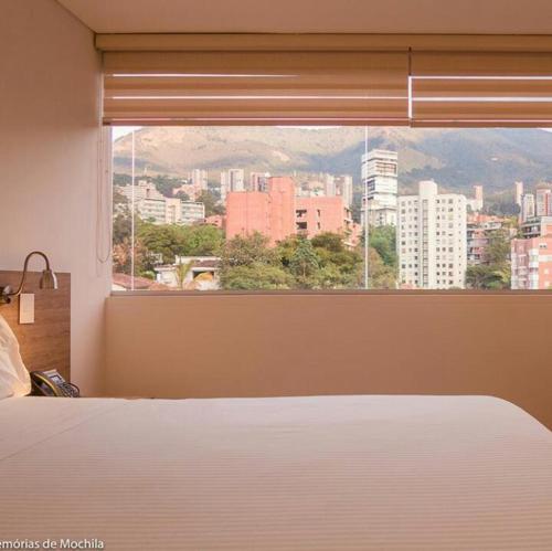 a bedroom with a view of a city from a window at Hotel Lomas 10 in Medellín